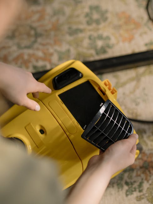 A person wearing yellow rubber gloves is placing a lit, illuminated sign with black letters reading 'CLEANING HOME' on a table, indicating domestic cleaning services. The background shows a blurred in