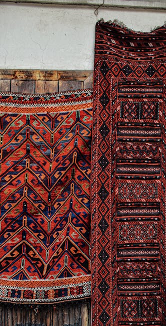 A large assortment of rolled and stacked traditional oriental rugs with intricate patterns and vibrant colors, including reds, oranges, blues, and beiges, displayed vertically and horizontally in a te